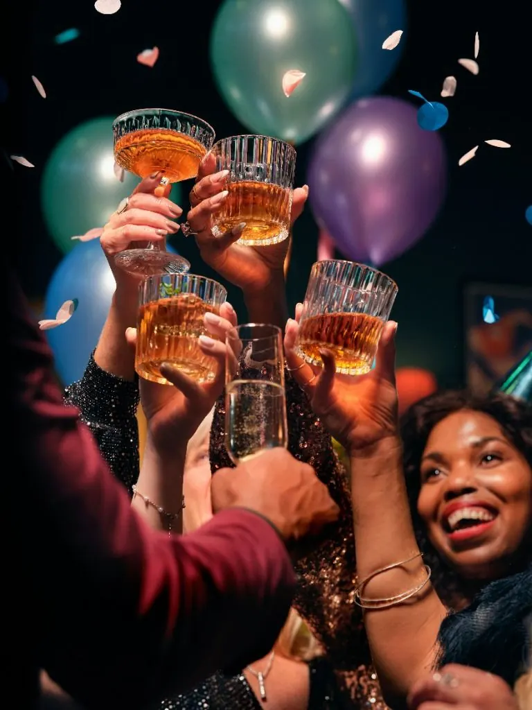 Des amis trinquent entre ballons et confettis lors d’une fête d’anniversaire