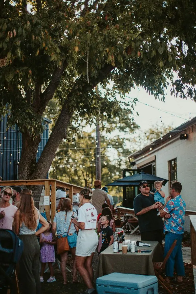 Des invités discutent à l’ombre d’un grand arbre lors d’une fête d’été en plein air